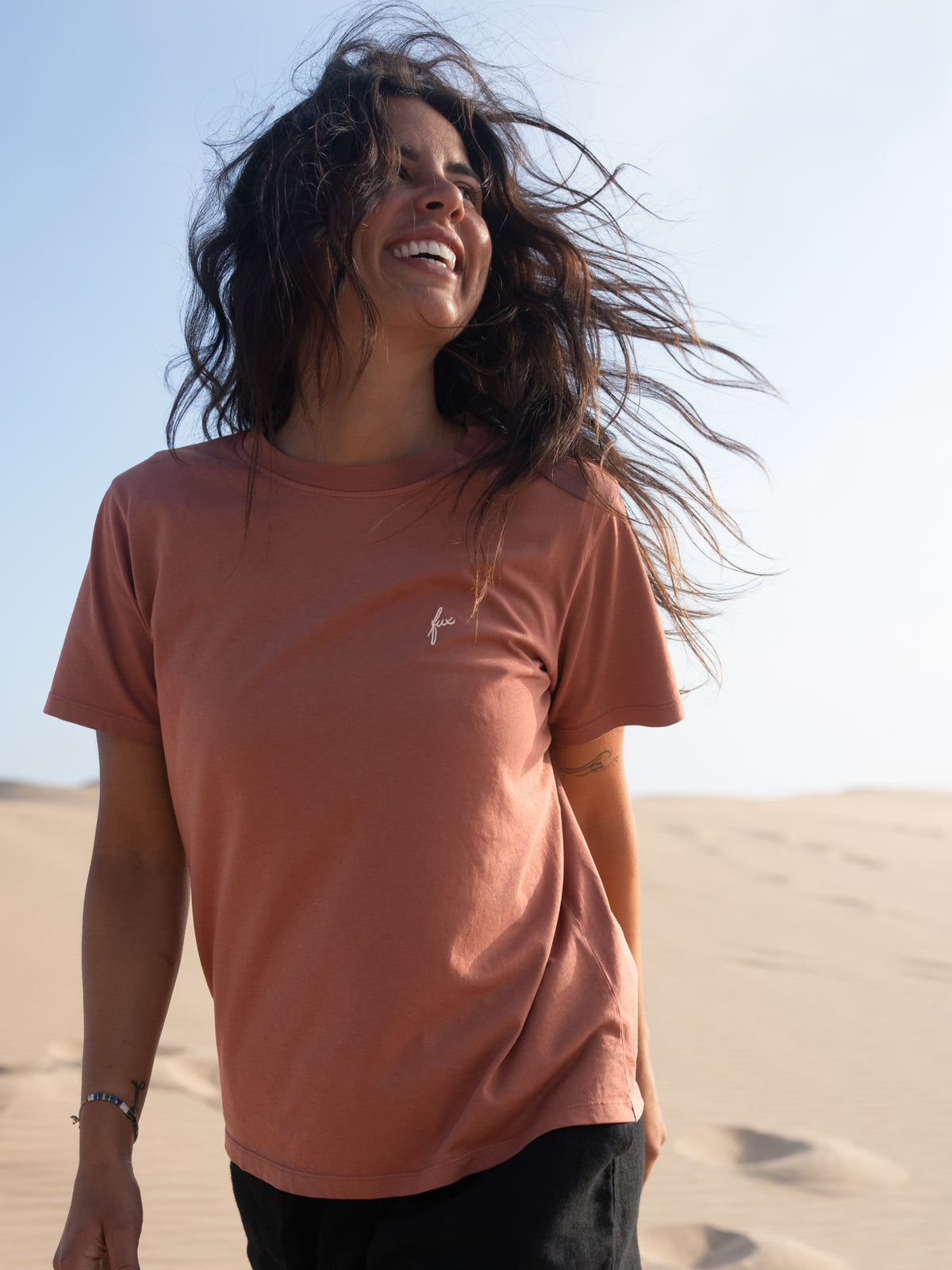 Frau trägt stückgefärbtes rotes FUXBAU T-Shirt aus Biobaumwolle am Strand