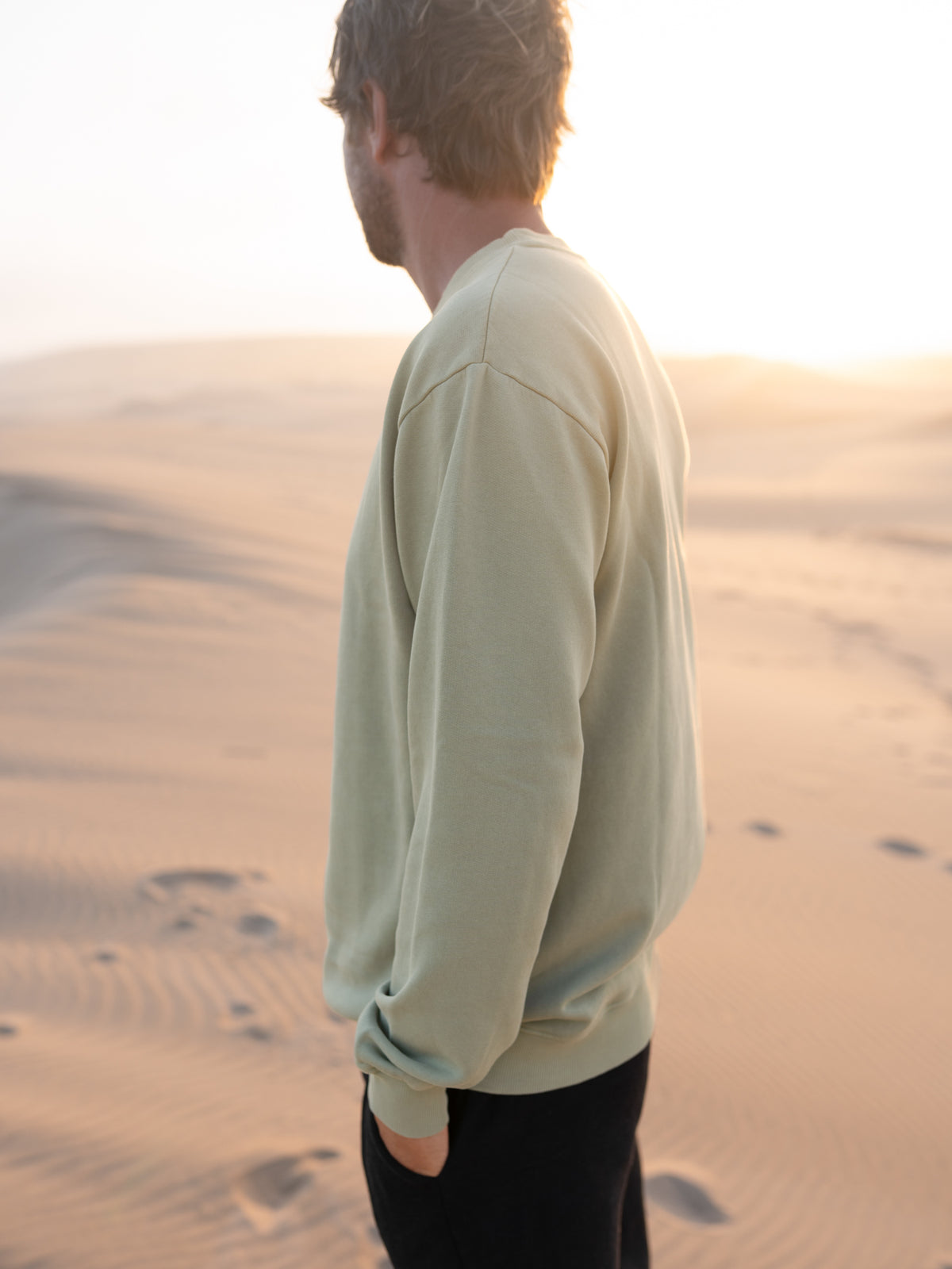SeegrĂŒner MĂ€nner Pullover von FUXBAU im Vintage Look vor heller DĂŒnenlandschaft