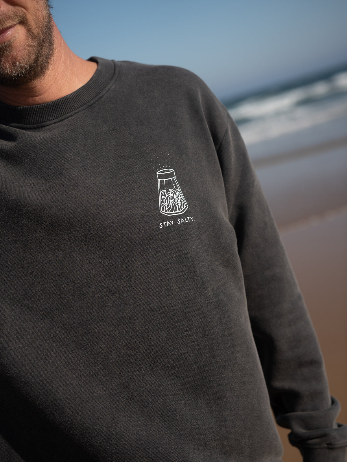 Detail des Stay Salty Prints auf salzschwarzem Sweater