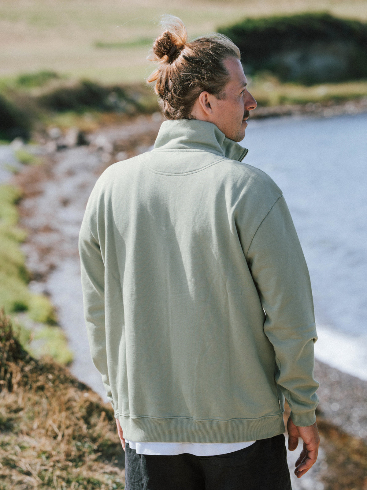 MĂ€nner Half Zip Sweater in Seegras aus Biobaumwolle von hinten am Meer