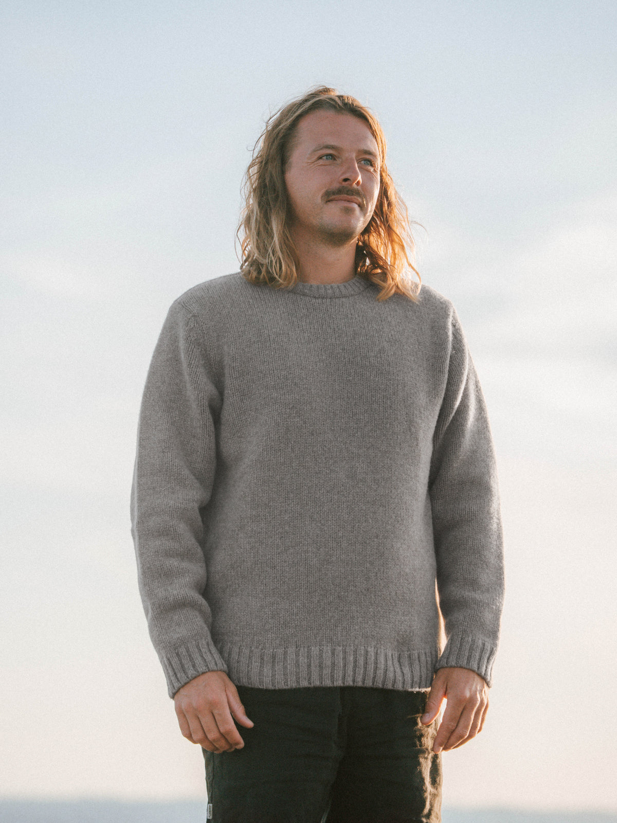 Ole trÀgt den MÀnner Merino Strickpullover in Braunmeliert aus 100 % Merinowolle, gestrickt in Deutschland