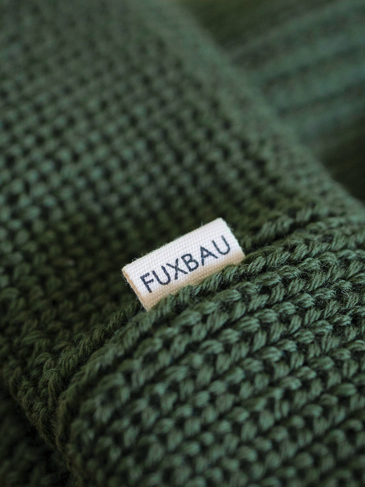 Detailaufnahme der FUXBAU Sideflag der kurzen Merino Fischermütze in waldgrün, GOTS zertifiziert und made in Germany