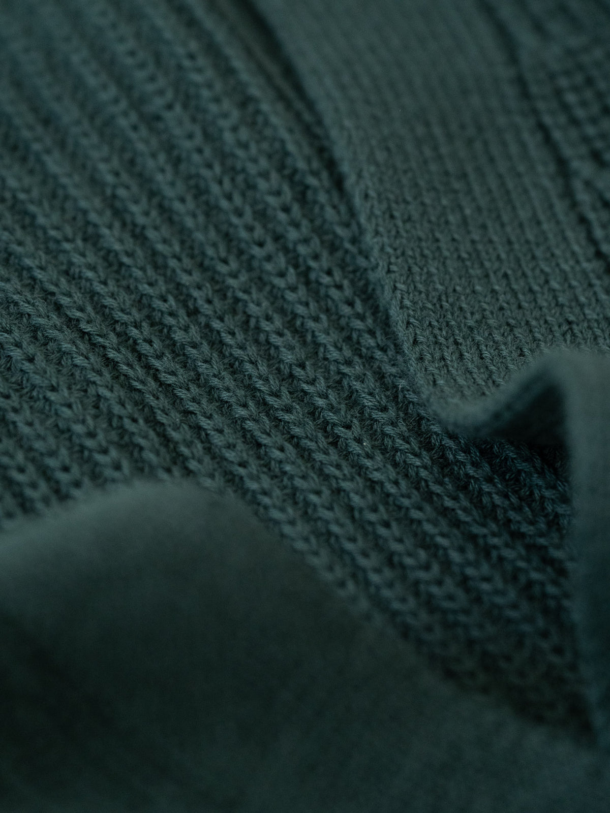 Detailansicht eines Strickmusters von einer FUXBAU Fair Fashion Strickjacke gefertigt in Italien in dunkelgrün.