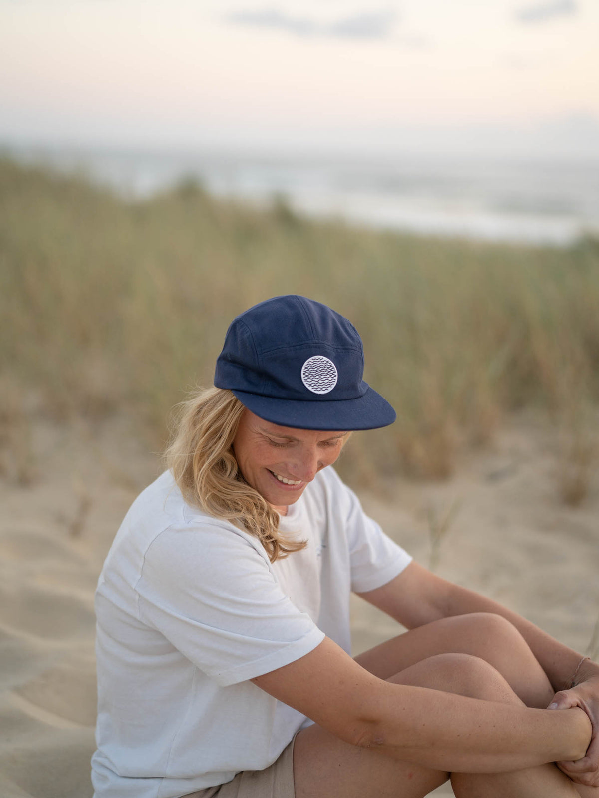 Isi trägt unsere FUXBAU Lost in Lines Cap mit Wellen-Patch am Strand