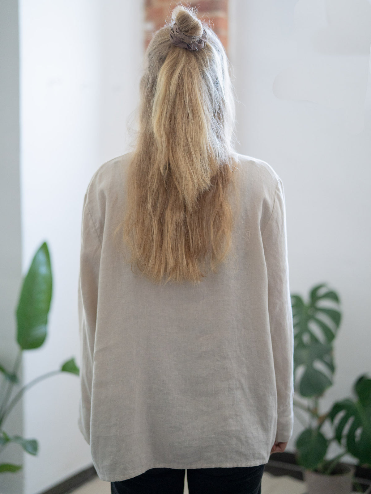 Rückansicht einer Fair Fashion Frauen Leinenbluse von FUXBAU in cremeweiss aus 100% Leinen gefertigt in Portugal unter fairen Bedingungen. Getragen von einer jungen, blonden Frau in Münster.