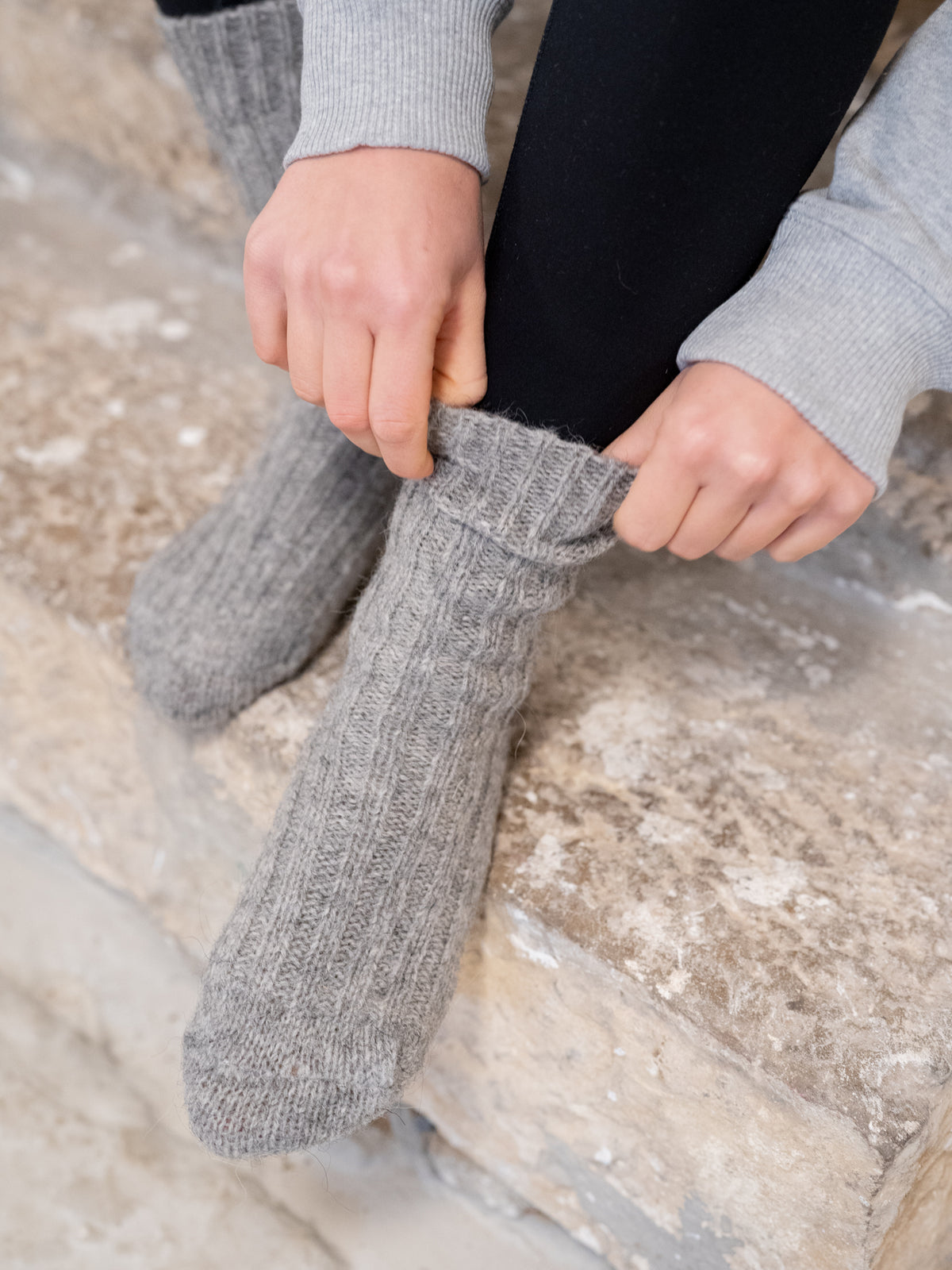 Greta trÀgt unsere kuschligen und weichen Alpaka Schafwollsocken in grau aus Alpaka und europÀischer Schafwolle made in Portugal.