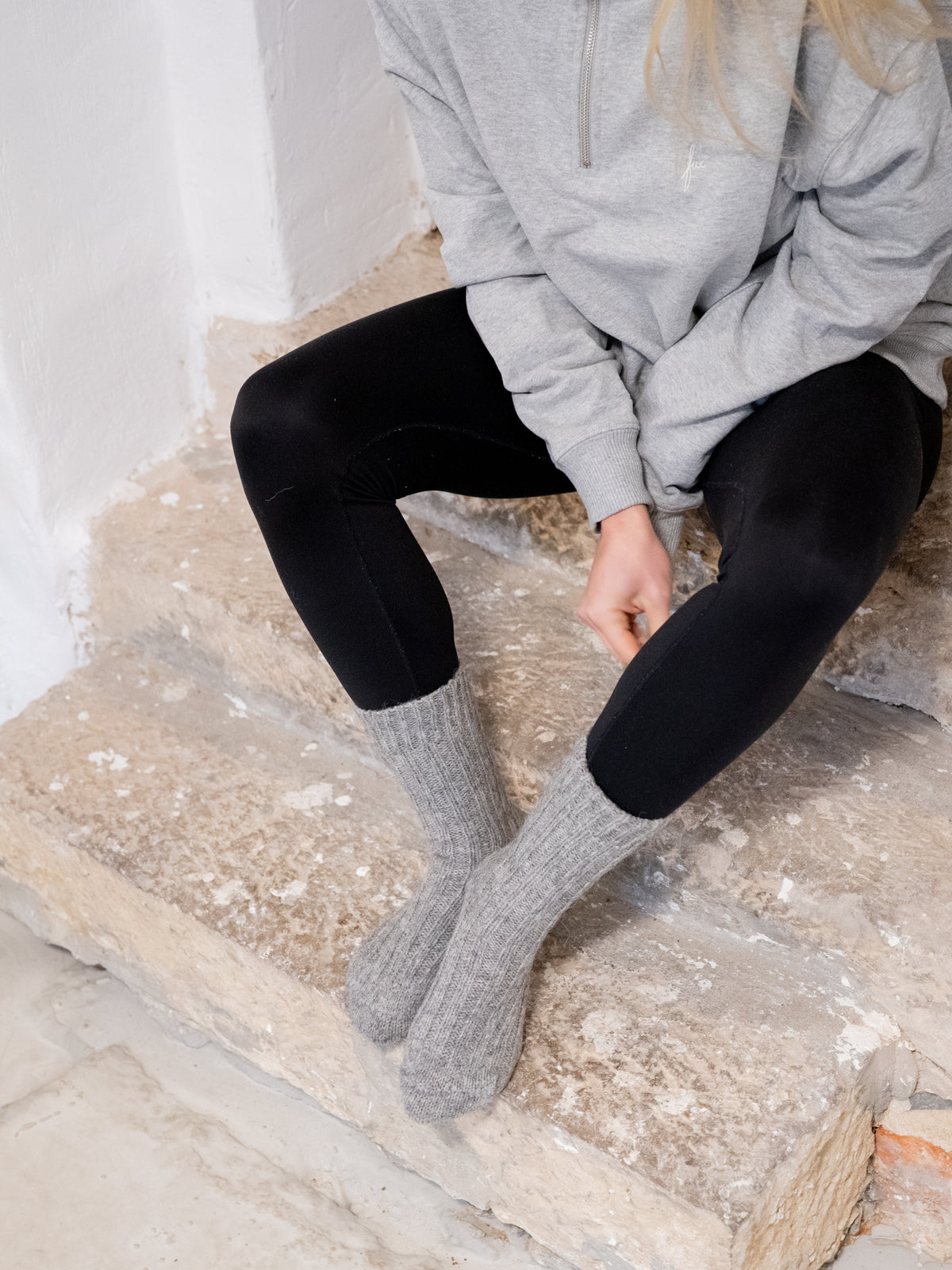Greta trÀgt unsere kuschligen und weichen Alpaka Schafwollsocken in grau, die fair produziert werden