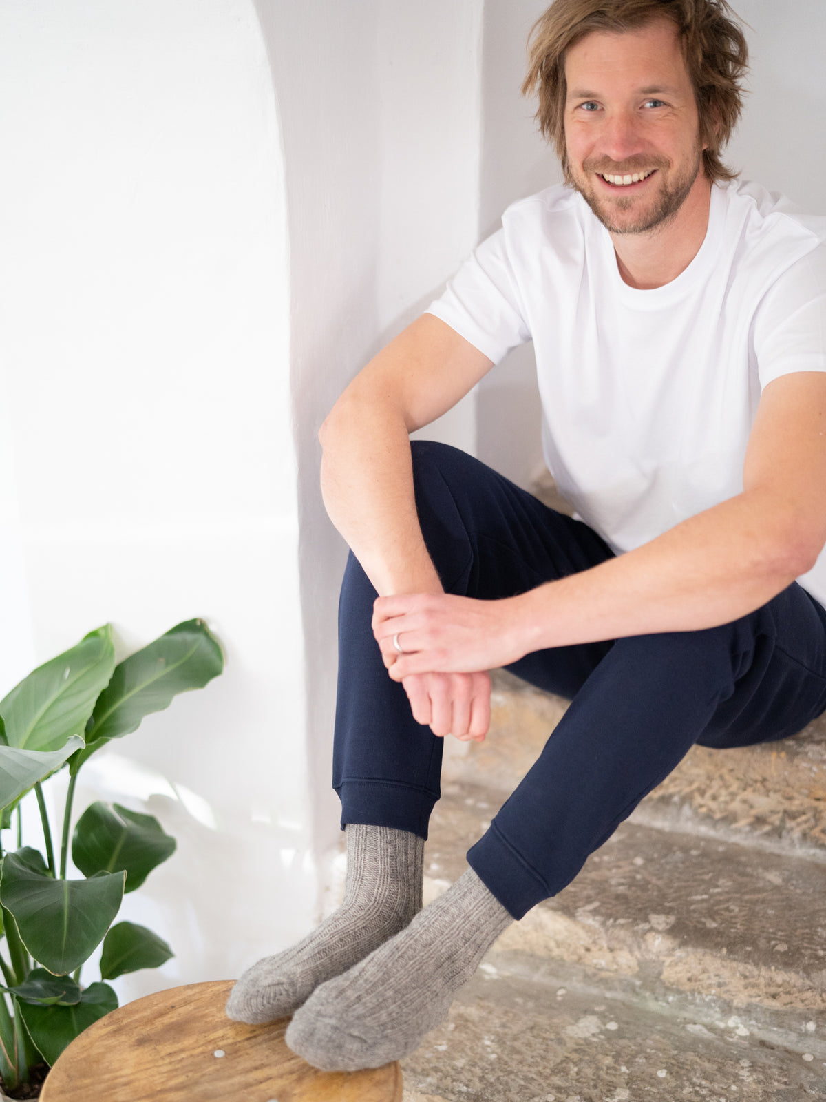 Kenny trÀgt unsere kuschligen und weichen Alpaka Schafwollsocken in grau, die fair produziert werden