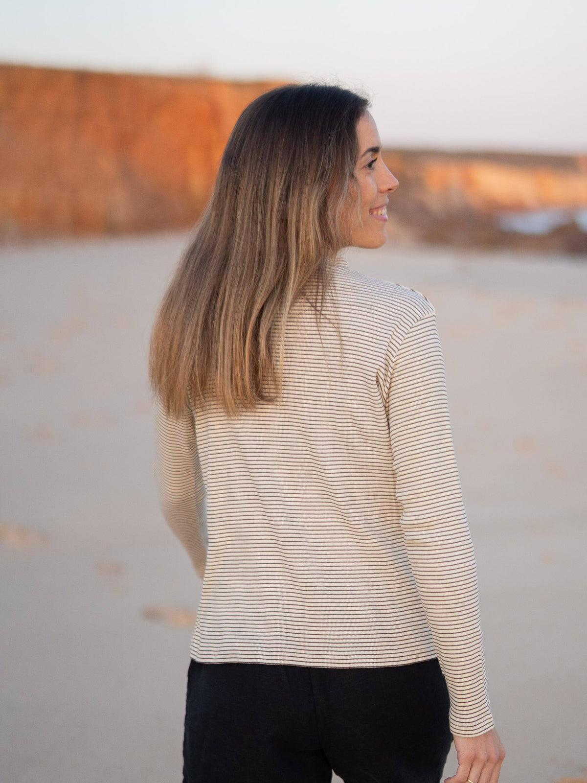 FUXBAU Fair Fashion Fitted Stehkragen Longsleeve creme braun gestreift aus GOTS-zertifizierter Biobaumwolle Made in Portugal getragen am Strand in Portugal.