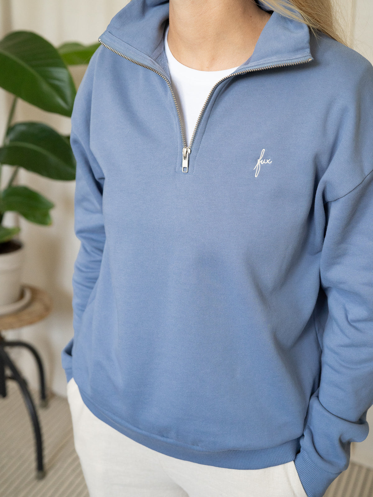 Himmelblauer Half-Zip-Sweater aus Biobaumwolle in Kombination mit weiĂźem Shirt und heller Hose