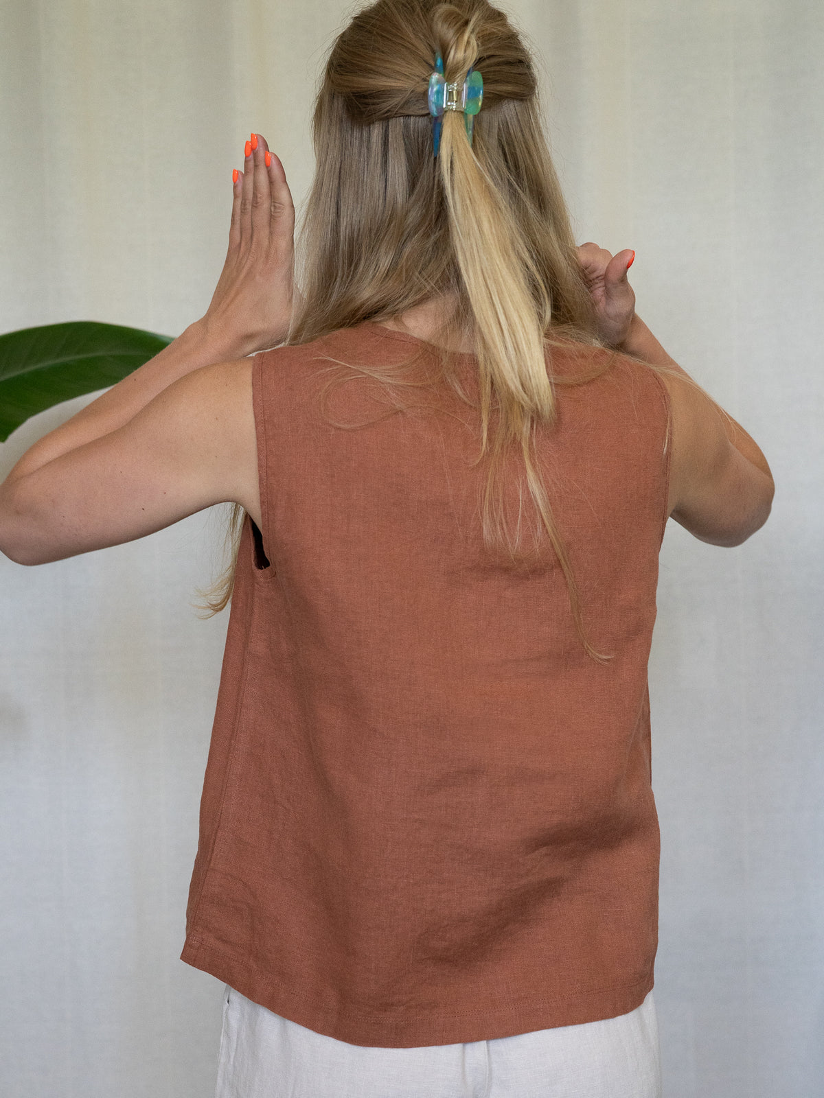 Frau trĂ€gt Ă€rmelloses Leinentop in Rostbraun â Sommermode aus 100% Leinen von FUXBAU, fair produziert in Europa, perfekt fĂŒr heiĂe Tage