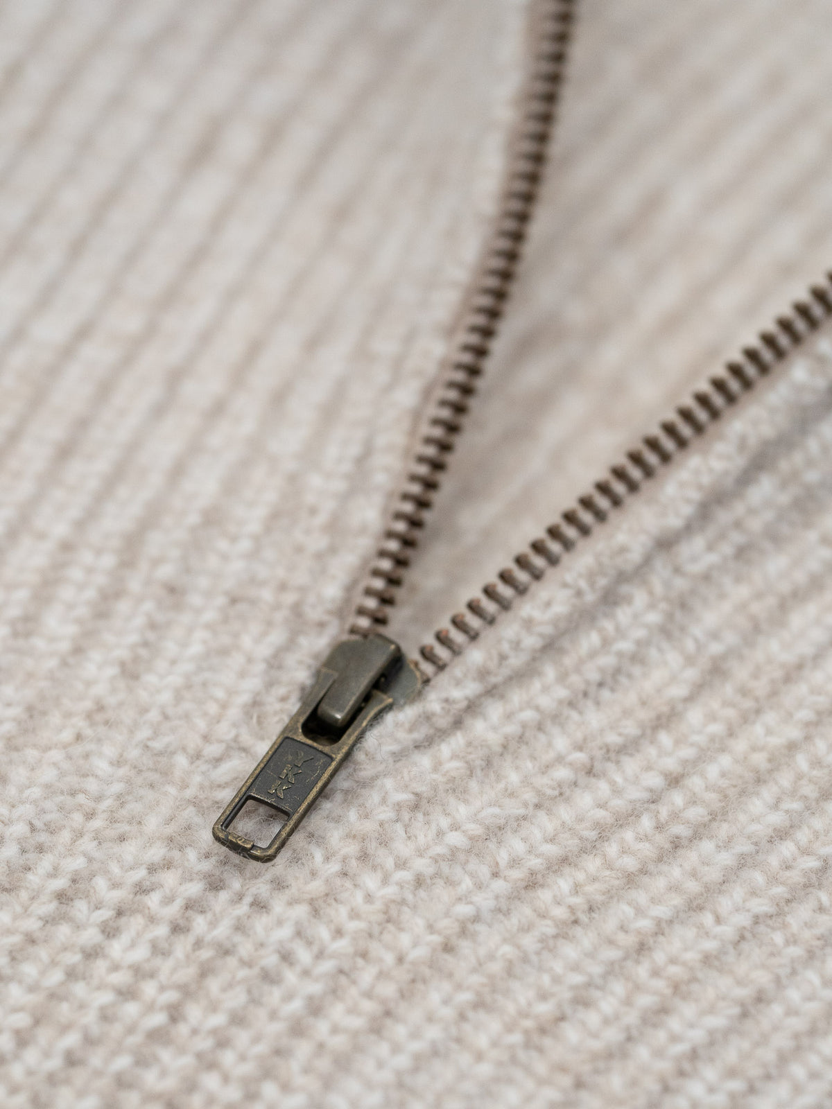 Detailansicht eines fairen Troyer aus 100% Merinowolle in beigemeliert von FUXBAU mit einem hochwertigen YKK Zipper.