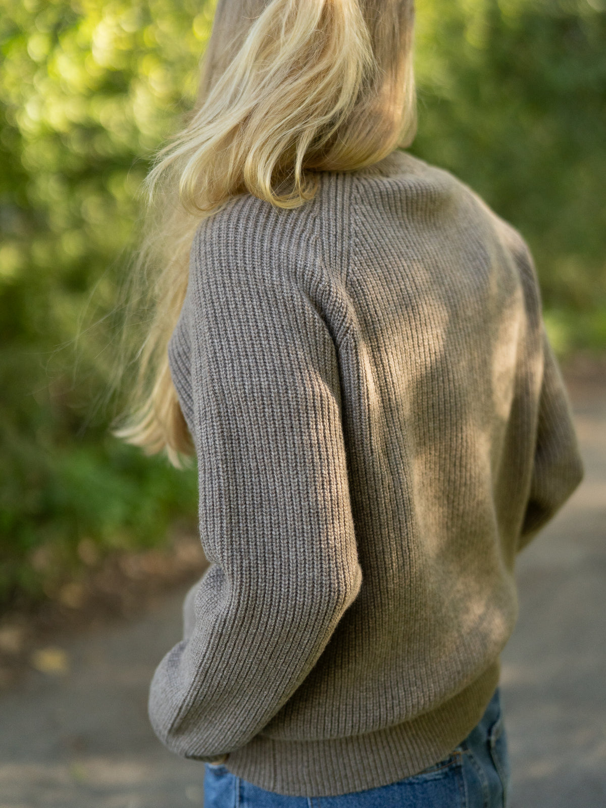 Fair Fashion Frauen Merino Troyer in braun meliert aus 100% Merino Schurwolle Made in Italy, getragen von einer jungen Frau mit einer RĂŒckansicht.