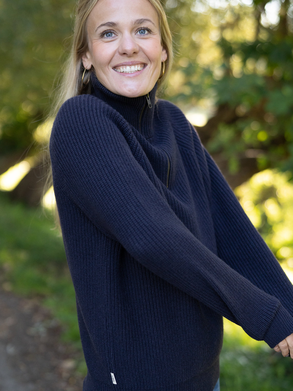 Fair Fashion Frauen Merino Troyer in navy aus 100% Merino Schurwolle Made in Italy, getragen von einer jungen Frau mit seitlicher Ansicht.