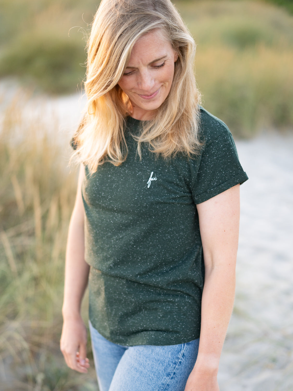 FUXBAU Fair Fashion Frauen T-Shirt in grĂŒn aus Biobaumwollen mit weiĂen Punkten getragen von einer jungen blonden Frau am Strand.