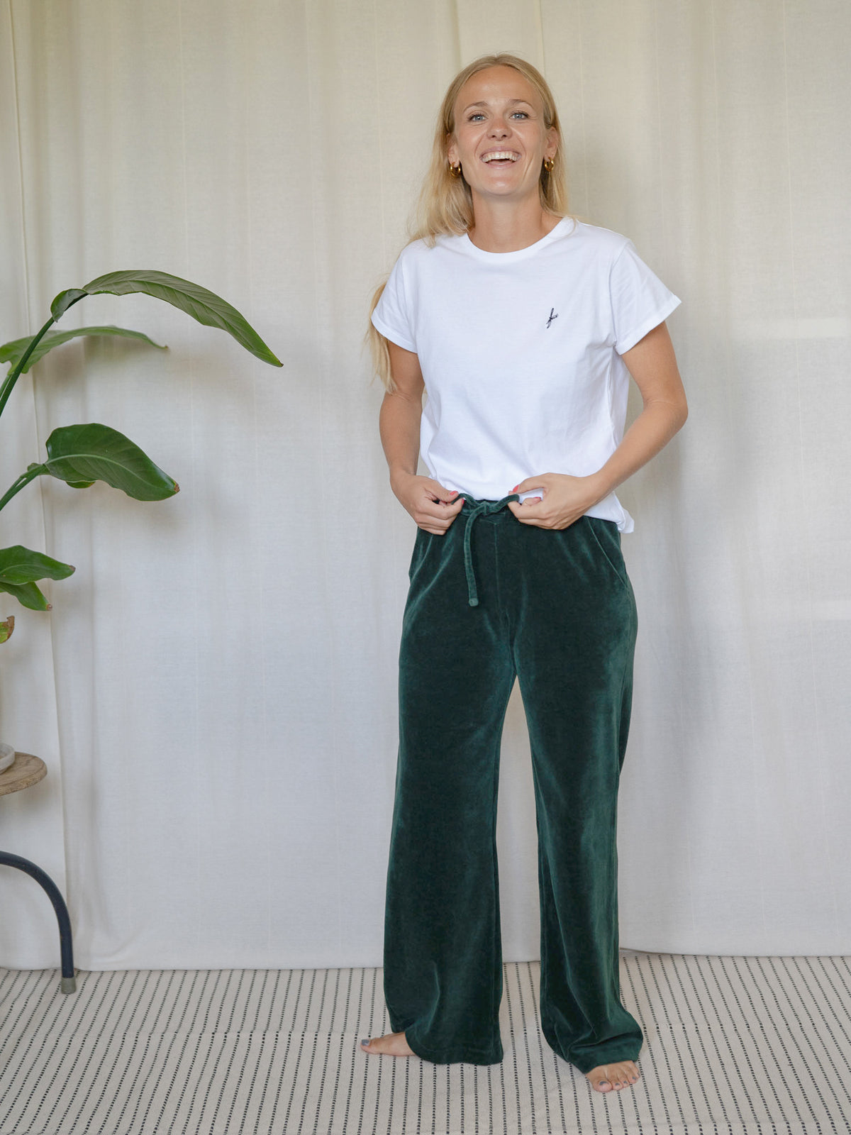 Frau trägt die dunkelgrüne FUXBAU Samthose Greta aus GOTS-zertifizierter Biobaumwolle – Fair Fashion Hose mit weitem Bein.