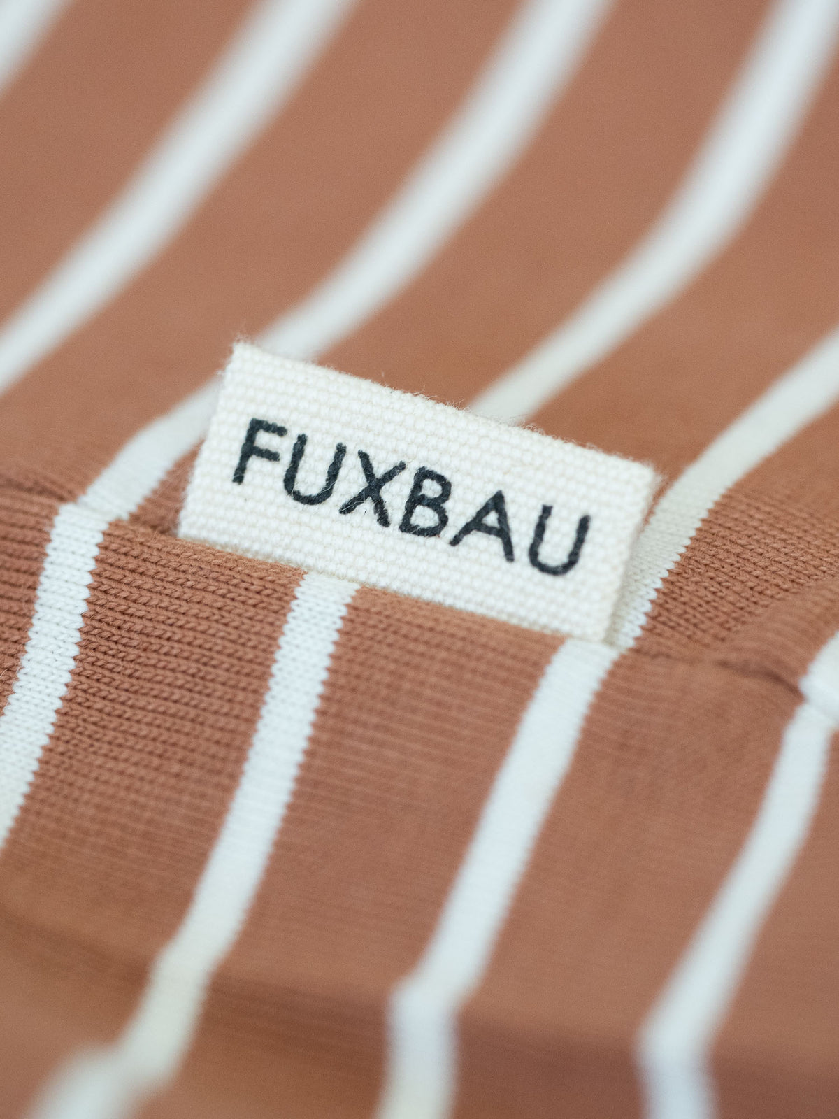 Detailansicht von einer Sideflags eines gestreiften FUXBAU Fair Fashion T-Shirt aus Biobaumwolle in schwarz, weiss und karamell.