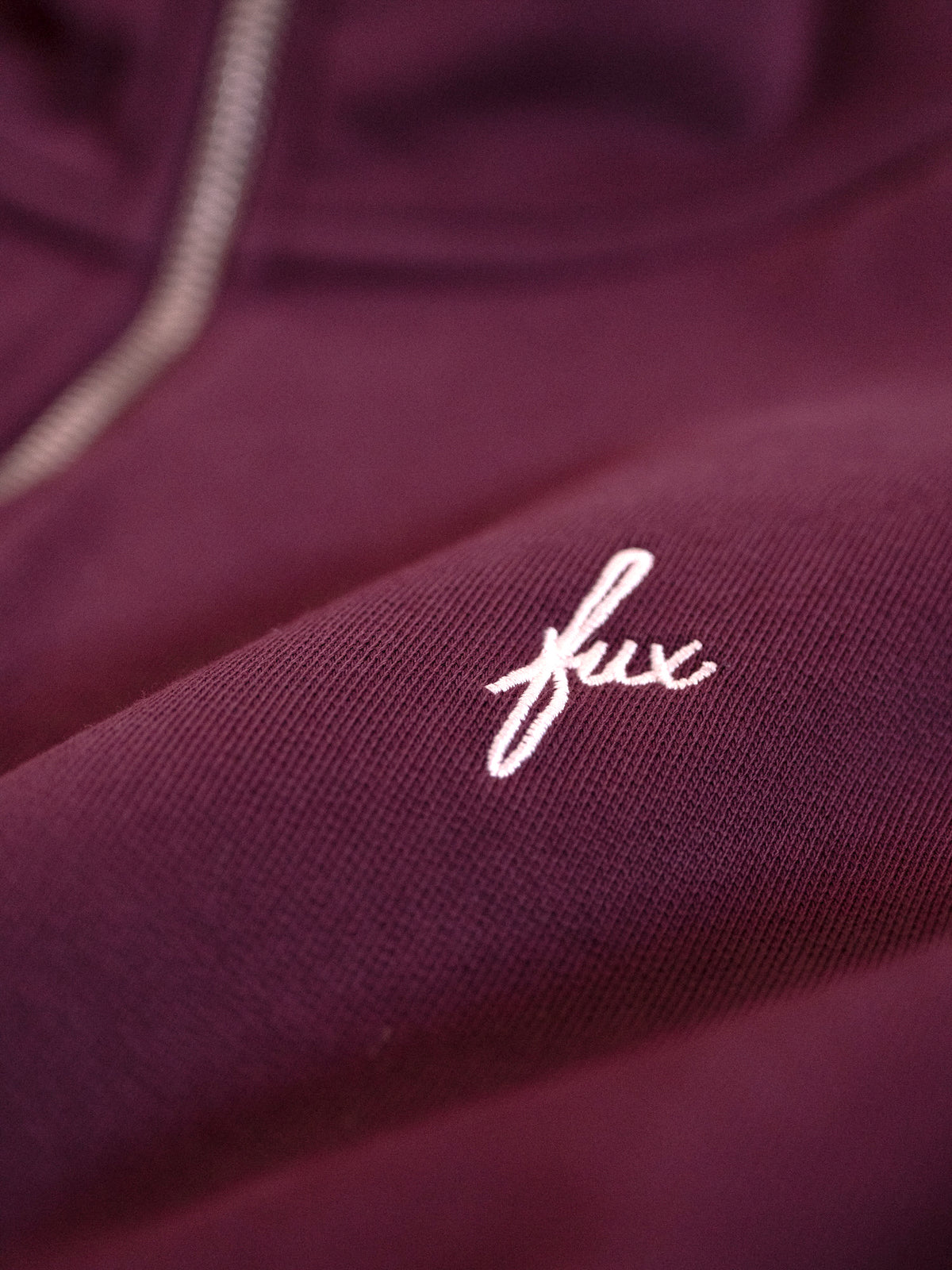 Detailaufnahme FUXBAU Sticklogo auf Half Zip Sweater aus GOTS-zertifizierter Bio-Baumwolle in Bordeaux – fair produziert in Portugal.