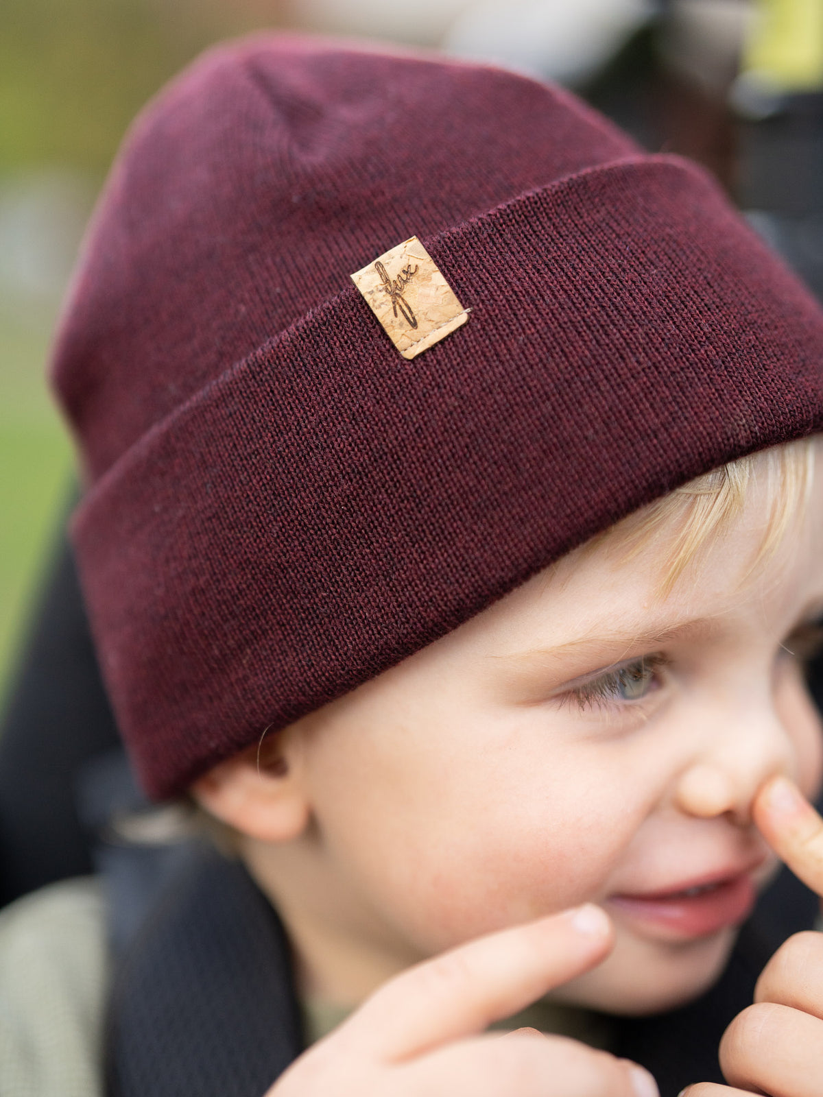Kind mit bordeauxfarbener FUXBAU Kinder Merino Kork Beanie aus 100% Merinowolle, fair produziert in Deutschland mit Kork-Logo-Patch.
