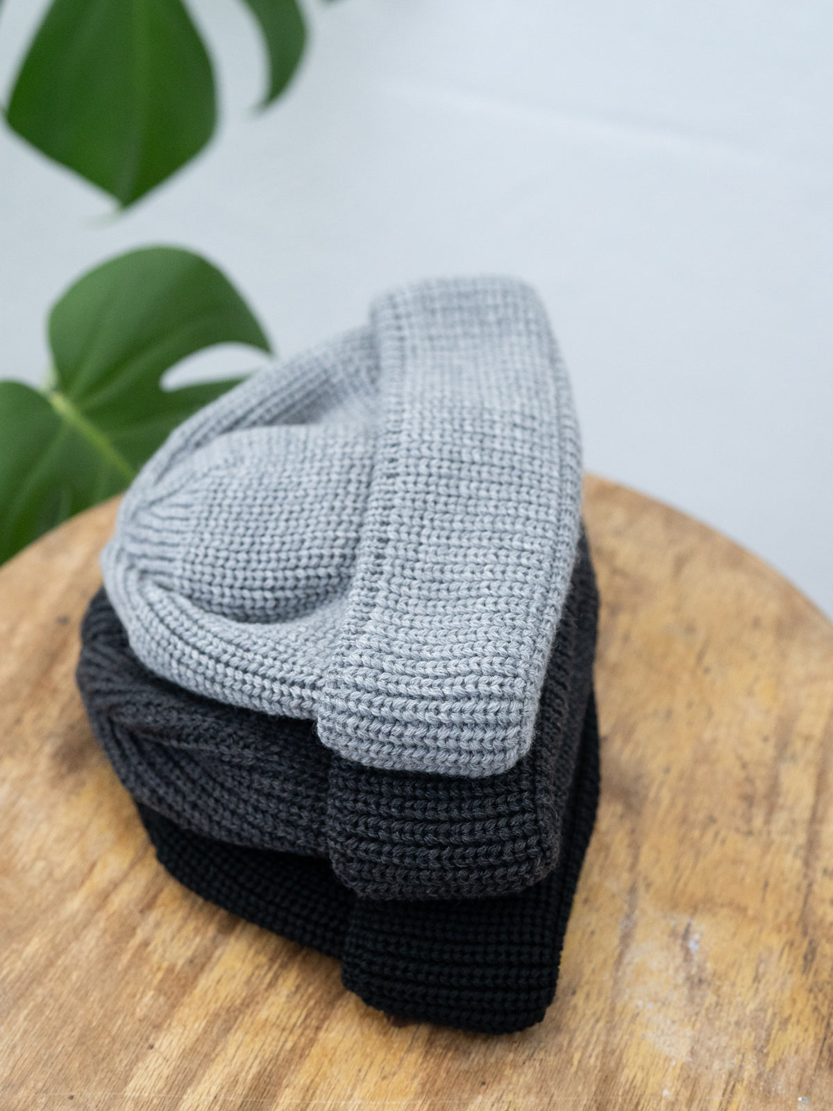 Stapel von FUXBAU Fair Fashion kurzen Merino Strickmützen aus 100% GOTS zertifizierter Merino Schurwolle.