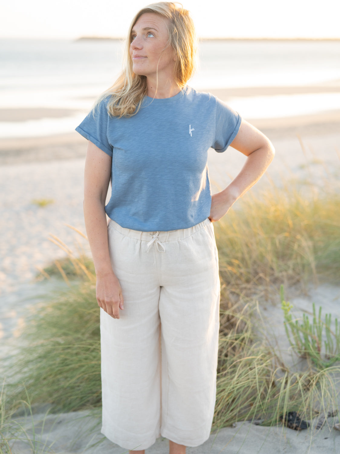Isi trägt das FUXBAU Frauen fux Azul T-Shirt in blau meliert aus 100% GOTS zertifizierter Biobaumwolle am Strand.