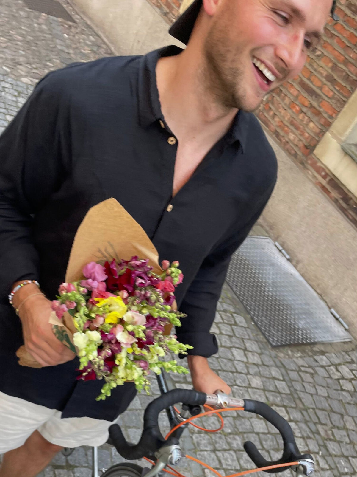 FUXBAU Fair Fashion MĂ€nner Leinenhemd Schwarz â Fredde, getragen mit BlumenstrauĂ und Fahrrad, handgefertigt in Portugal