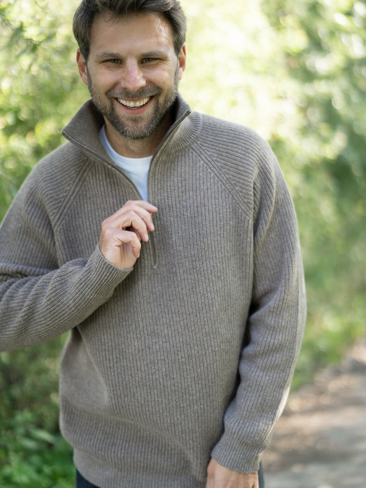 Fair Fashion Männer Merino Troyer in braun meliert aus 100% Merino Schurwolle Made in Italy, getragen von einem jungen Mann der in die Kamera lacht.