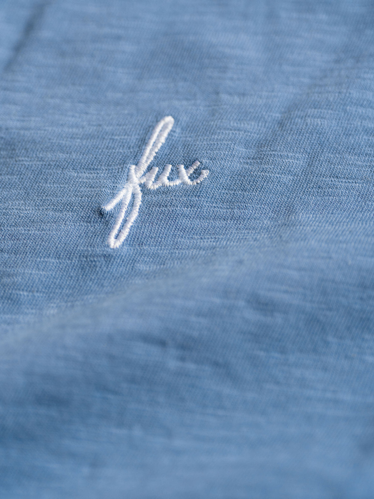 Detailansicht eines fux Sticks in weiß vom Fair Fashion Männer Azul T-Shirt von FUXBAU aus 100% GOTS Bio-Baumwolle.