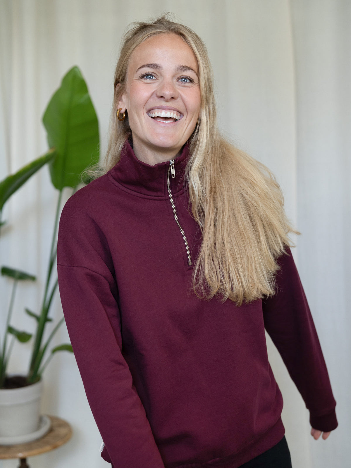 Frau trĂ€gt den bordeauxfarbenen FUXBAU Half-Zip Sweater â Fair Fashion Pullover aus Biobaumwolle, hergestellt in Portugal.