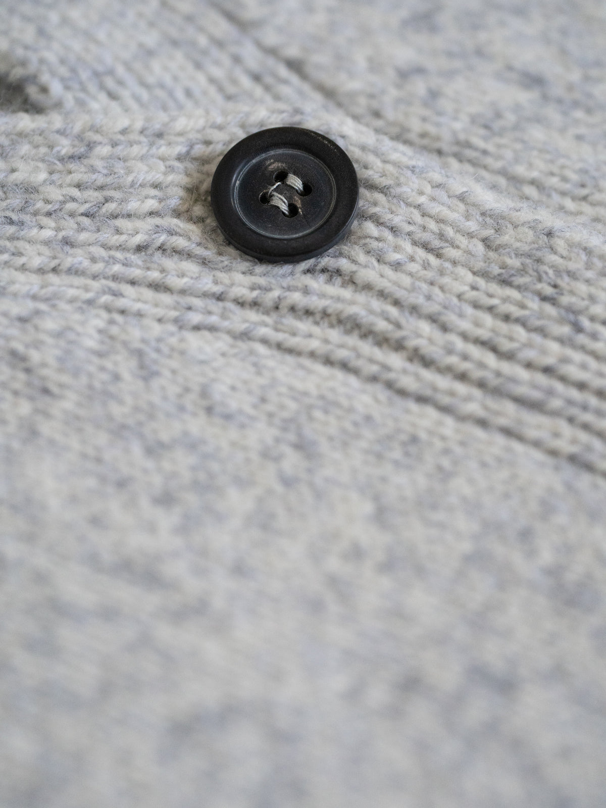 Detail des Knopfs der FUXBAU Merino Strickweste â feine Strickstruktur in Graumeliert, hochwertig verarbeitet