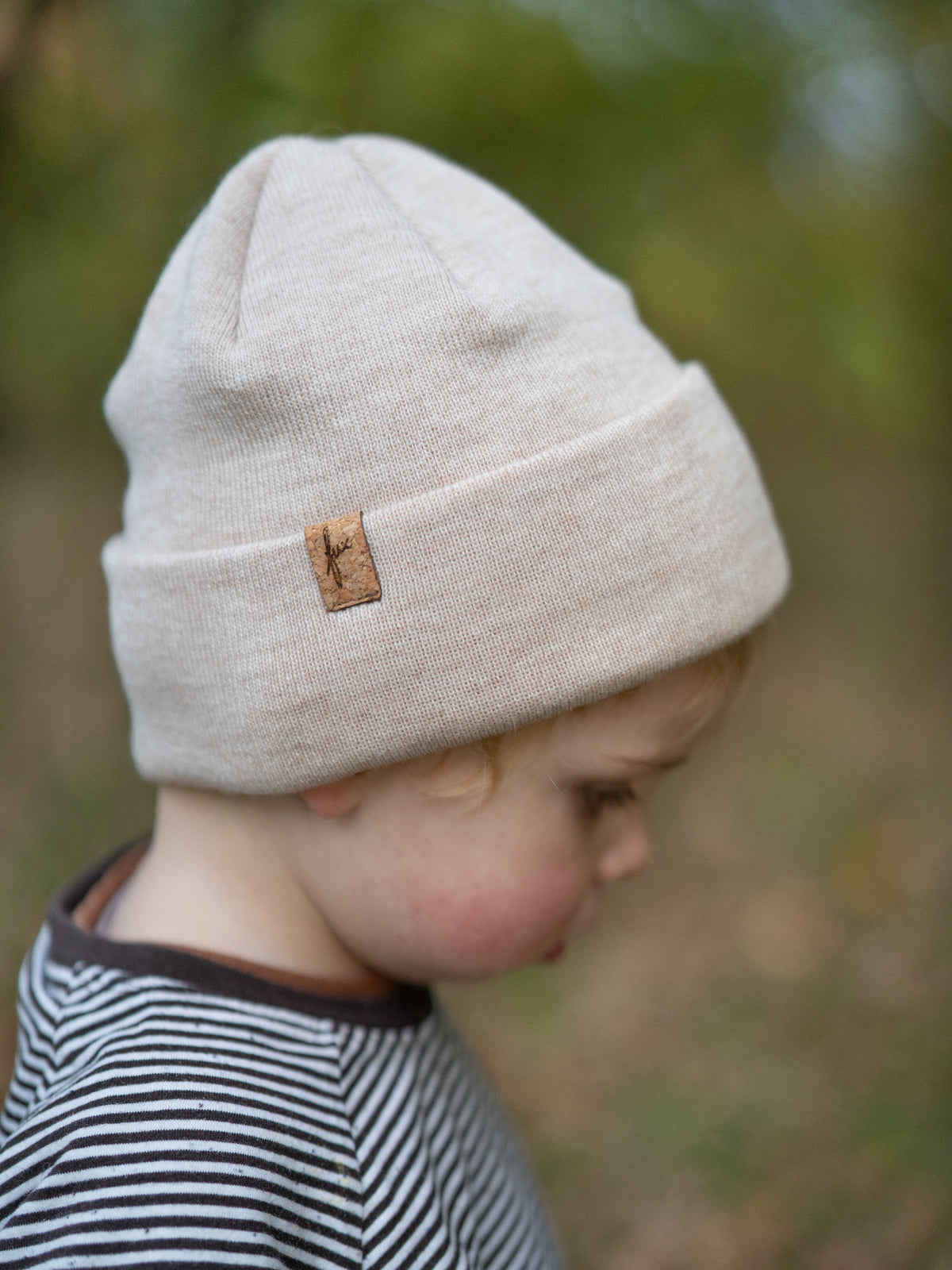 Kind trägt FUXBAU Kinder Beanie aus Merinowolle in Naturweiß – Mütze mit Korklabel, fair gefertigt in Deutschland