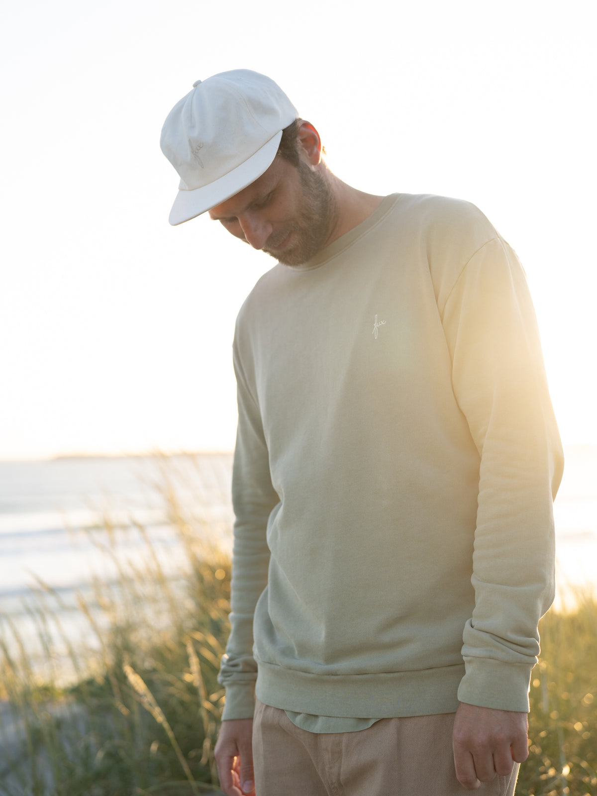 Fair produziertes MĂ€nner Sweatshirt seegrĂŒn getragen von einem jungen Mann am Meer