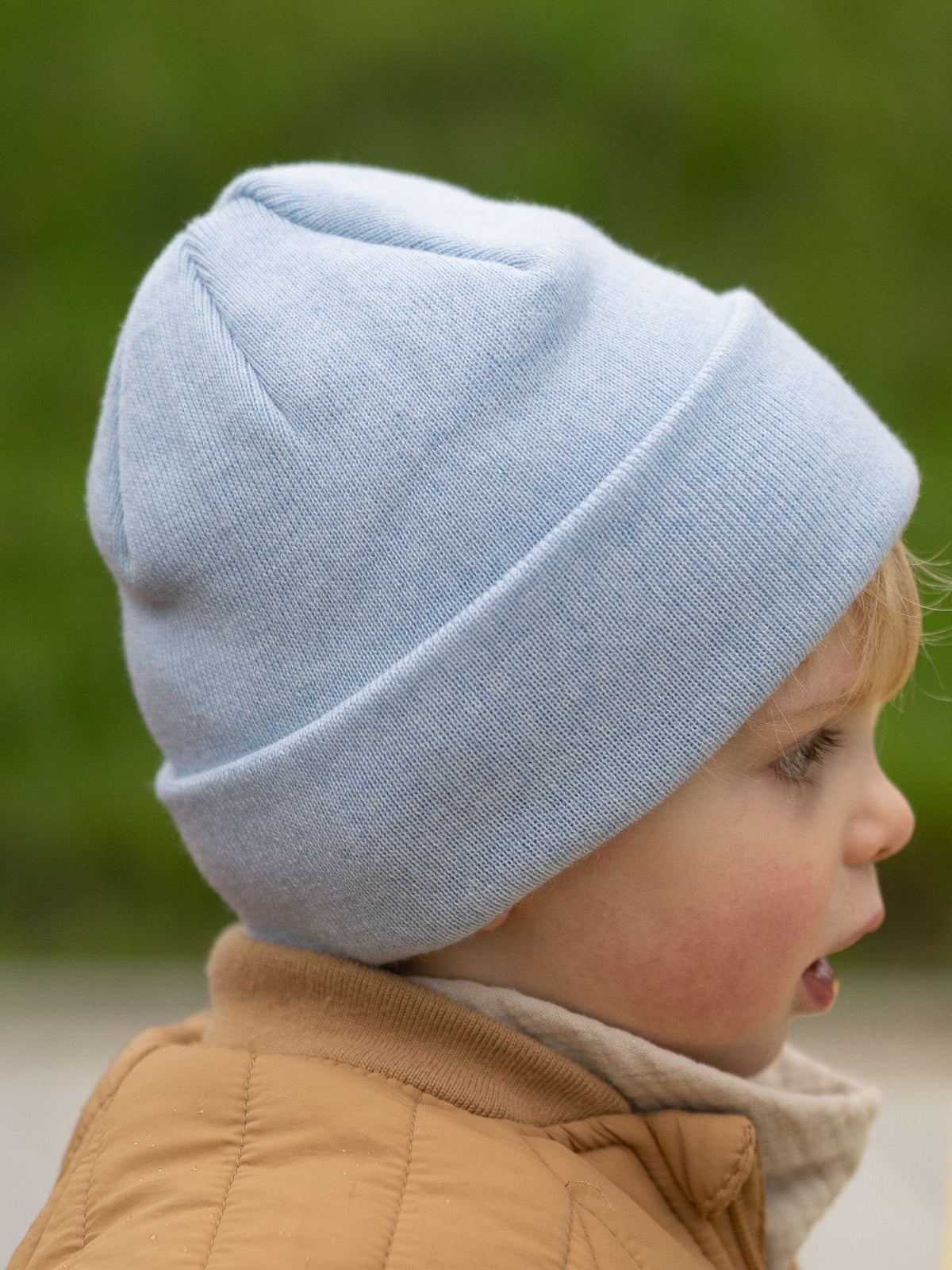 Seitliche Ansicht eines Kindes mit eisblauer FUXBAU Kinder Merino Kork Beanie – Fair Fashion Mütze aus Merinowolle, hergestellt in Deutschland.
