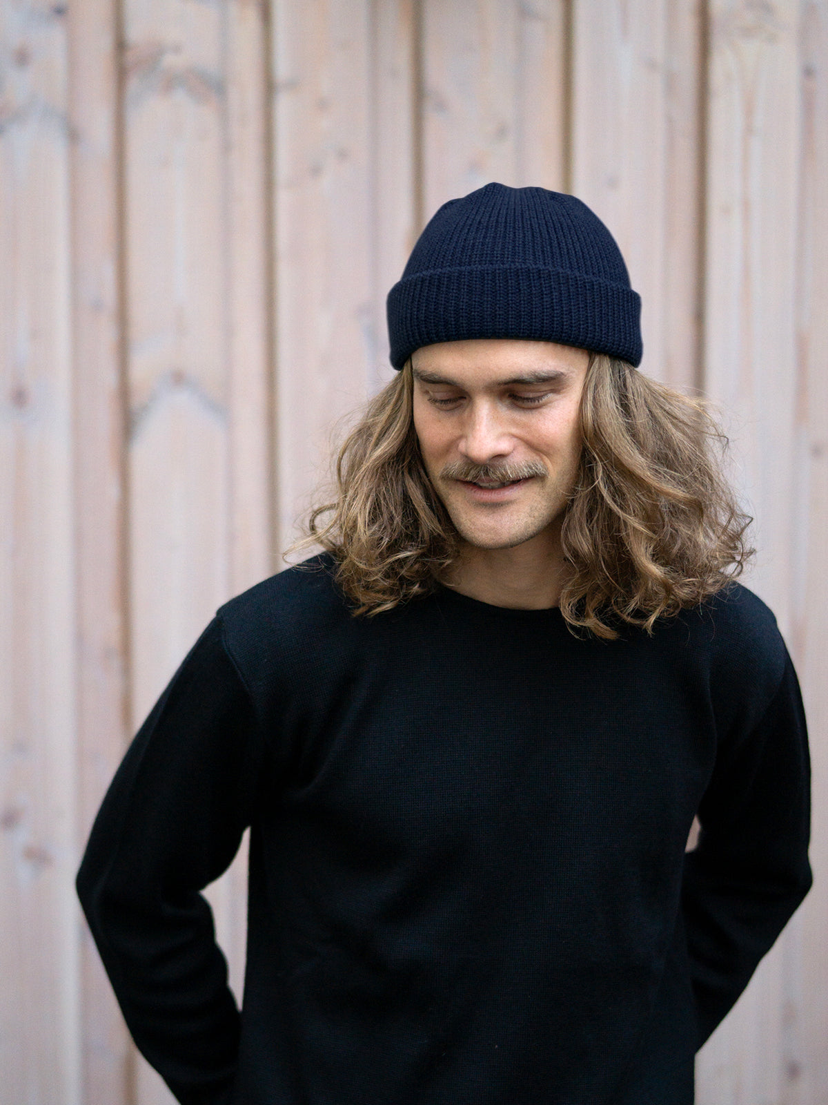 Unser Freund Kelsey trägt die Kurze Merino Strickmütze in navy von FUXBAU aus 100% GOTS zertifizierter Merinowolle made in Germany