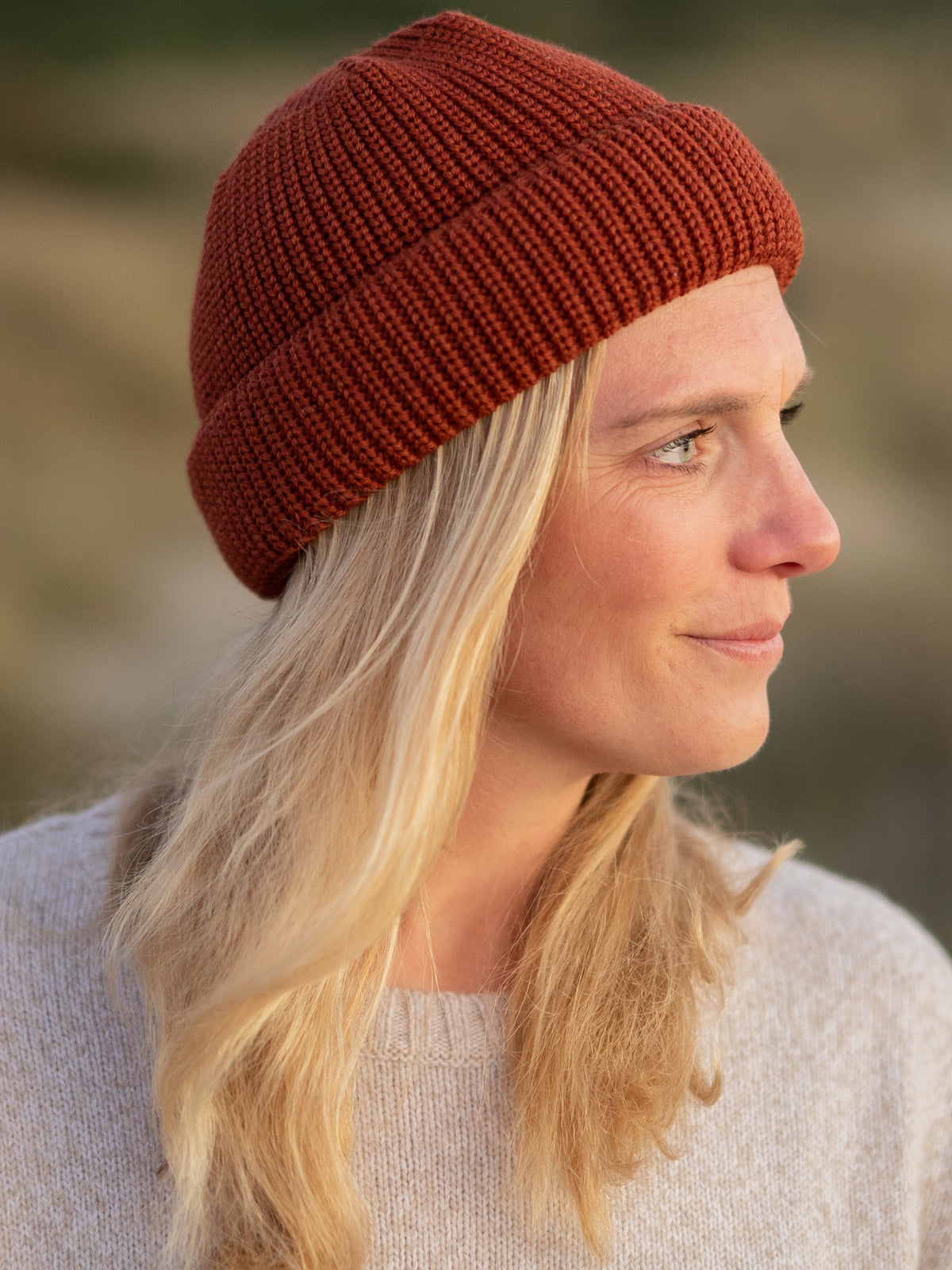 Fair Fashion kurze Fischermütze von FUXBAU aus GOTS-zertifizierter Merino Schurwolle. Gestrickt in Deutschland in herbstorange und getragen von einer jungen blonden Frau.