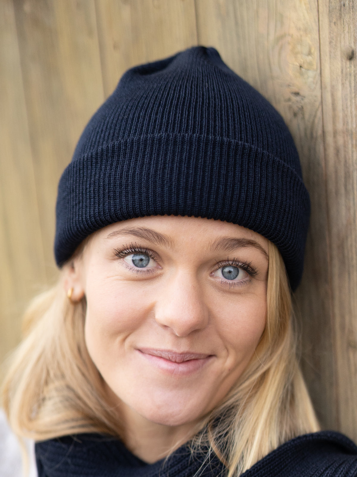 FUXBAU Fair Fashion Merino Strickmütze in Navy aus 100% GOTS zertifizierter Merino Schurwolle. Gestrickt in Deutschland und getragen von einer jungen blonden Frau.