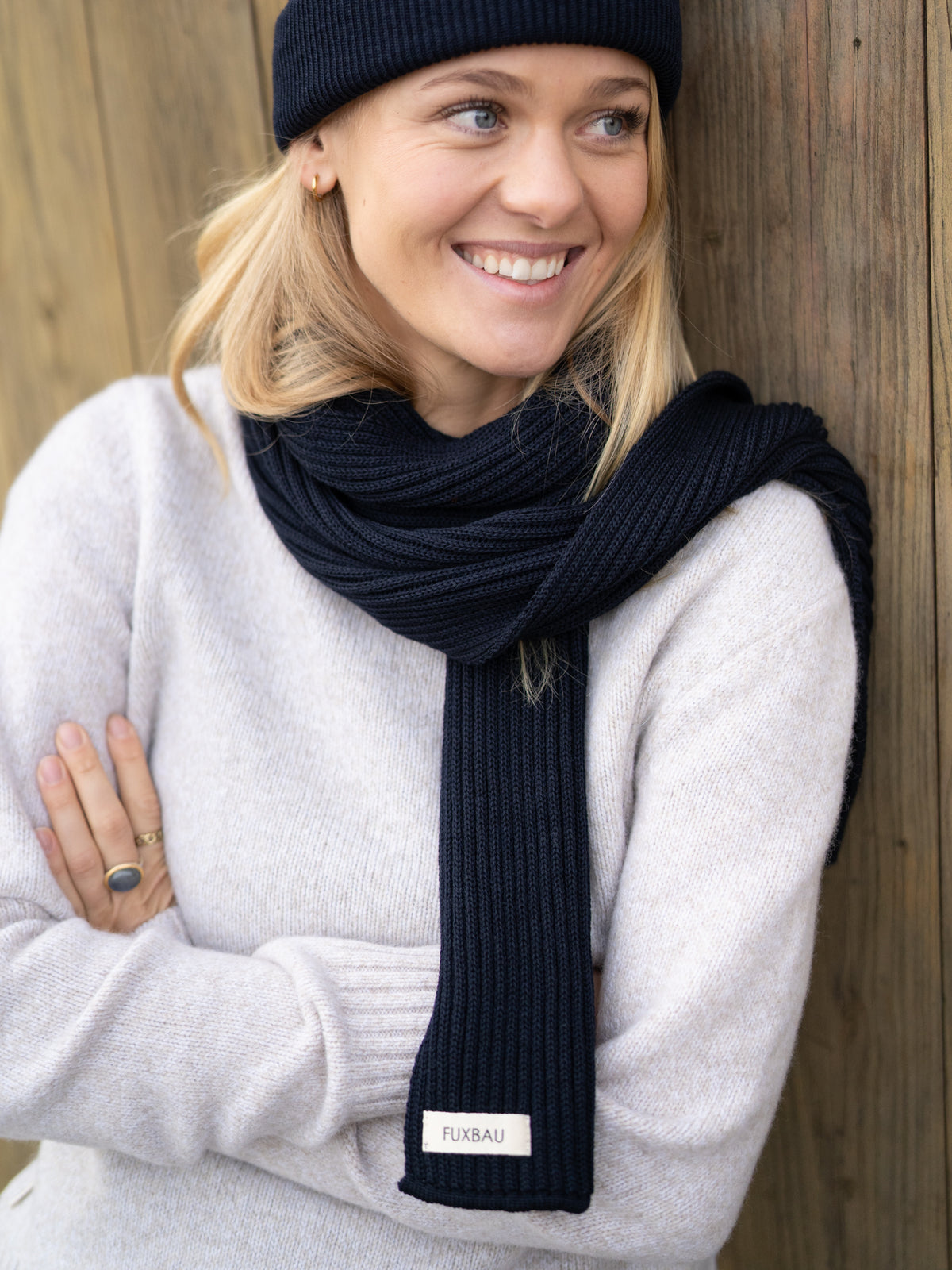 FUXBAU Fair Fashion Merino Schal in Navy aus 100% GOTS zertifizierter Merino Schurwolle. Gestrickt in Deutschland und getragen von einer jungen blonden Frau.