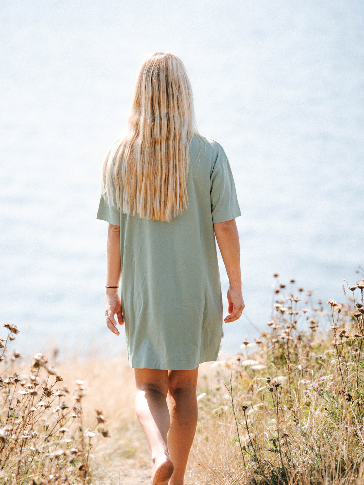 Frauen T-Shirt Kleid in Seegras aus Biobaumwolle von hinten am Meer