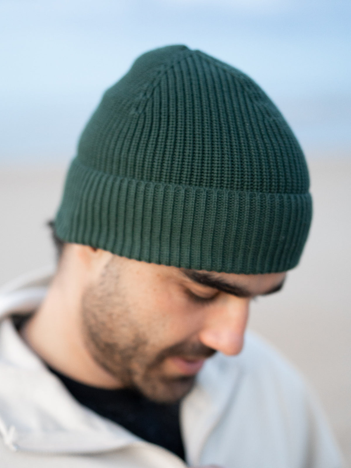 Guillermo trägt eine Fair Fashion Strickmütze von FUXBAU in grün aus 100% GOTS zertifizierter Biobaumwolle. Gestrickt in Italien.