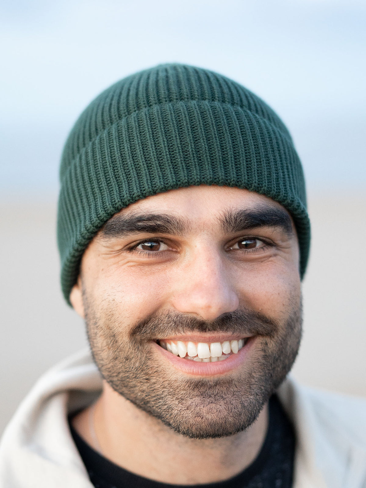 Guillermo trägt eine Fair Fashion Strickmütze von FUXBAU in grün aus 100% GOTS zertifizierter Biobaumwolle. Gestrickt in Italien.