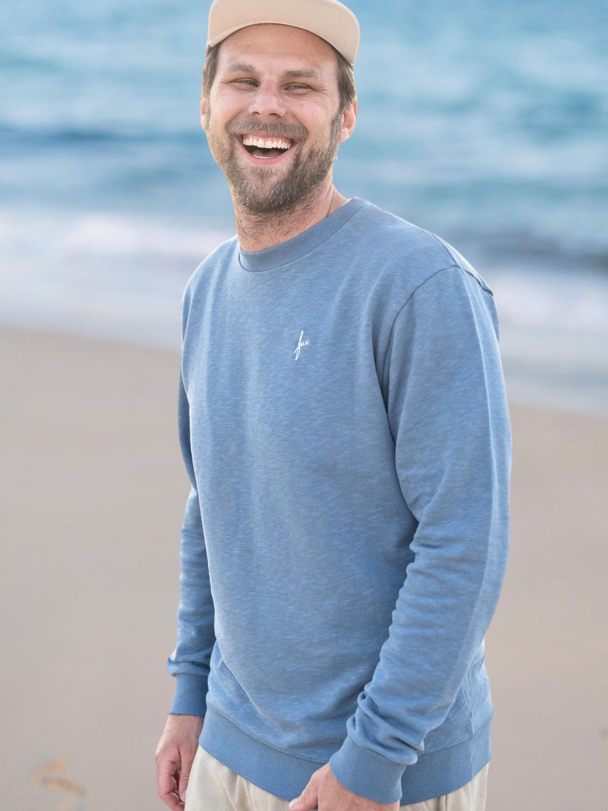Philipp trägt den Männer fux Azul Sweater in Blau meliert am Strand in Portugal – 100 % Bio-Baumwolle, GOTS-zertifiziert