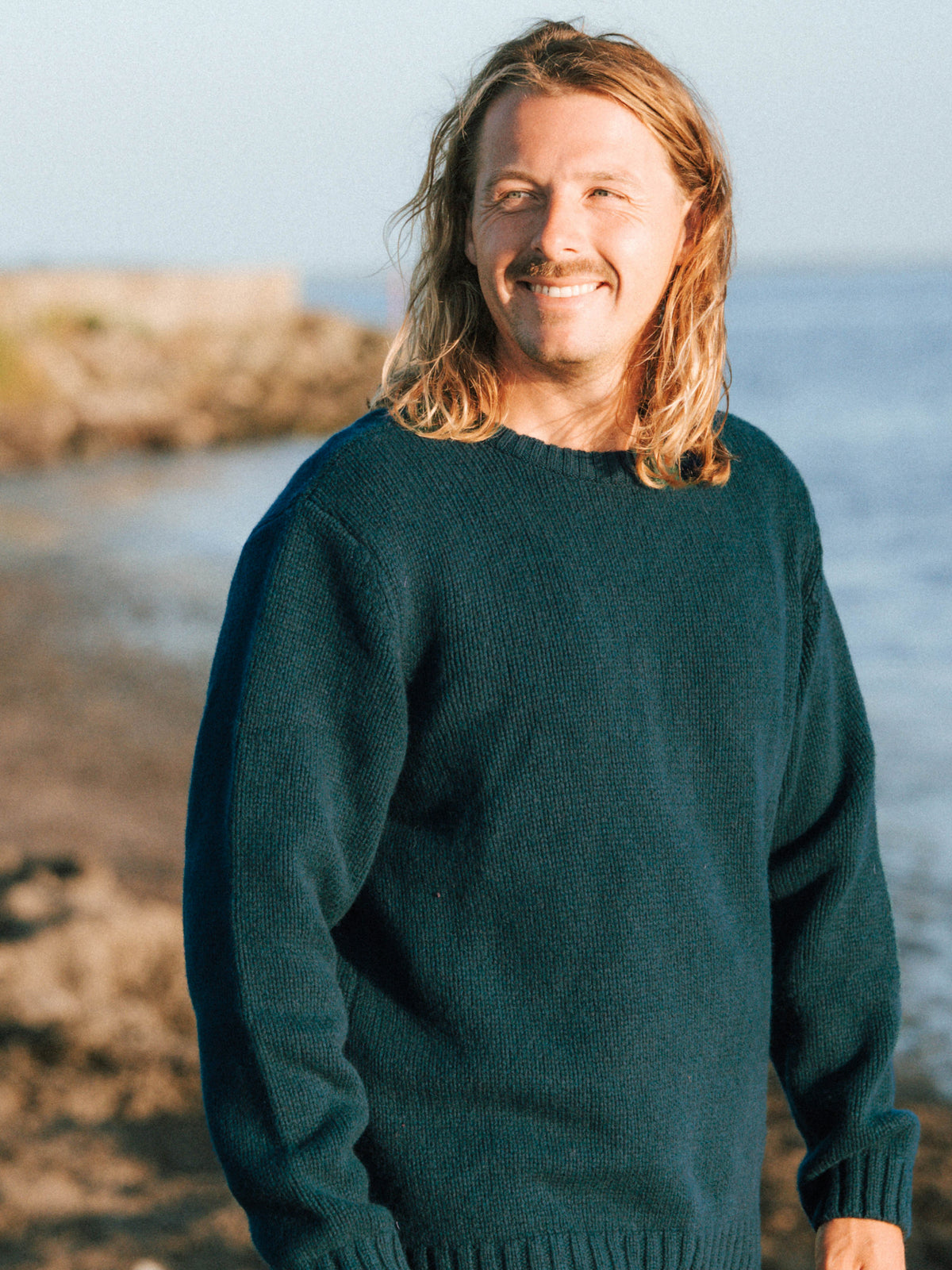 Ole trägt den Männer Merino Strickpullover in Grün aus 100 % Merinowolle, gestrickt in Deutschland
