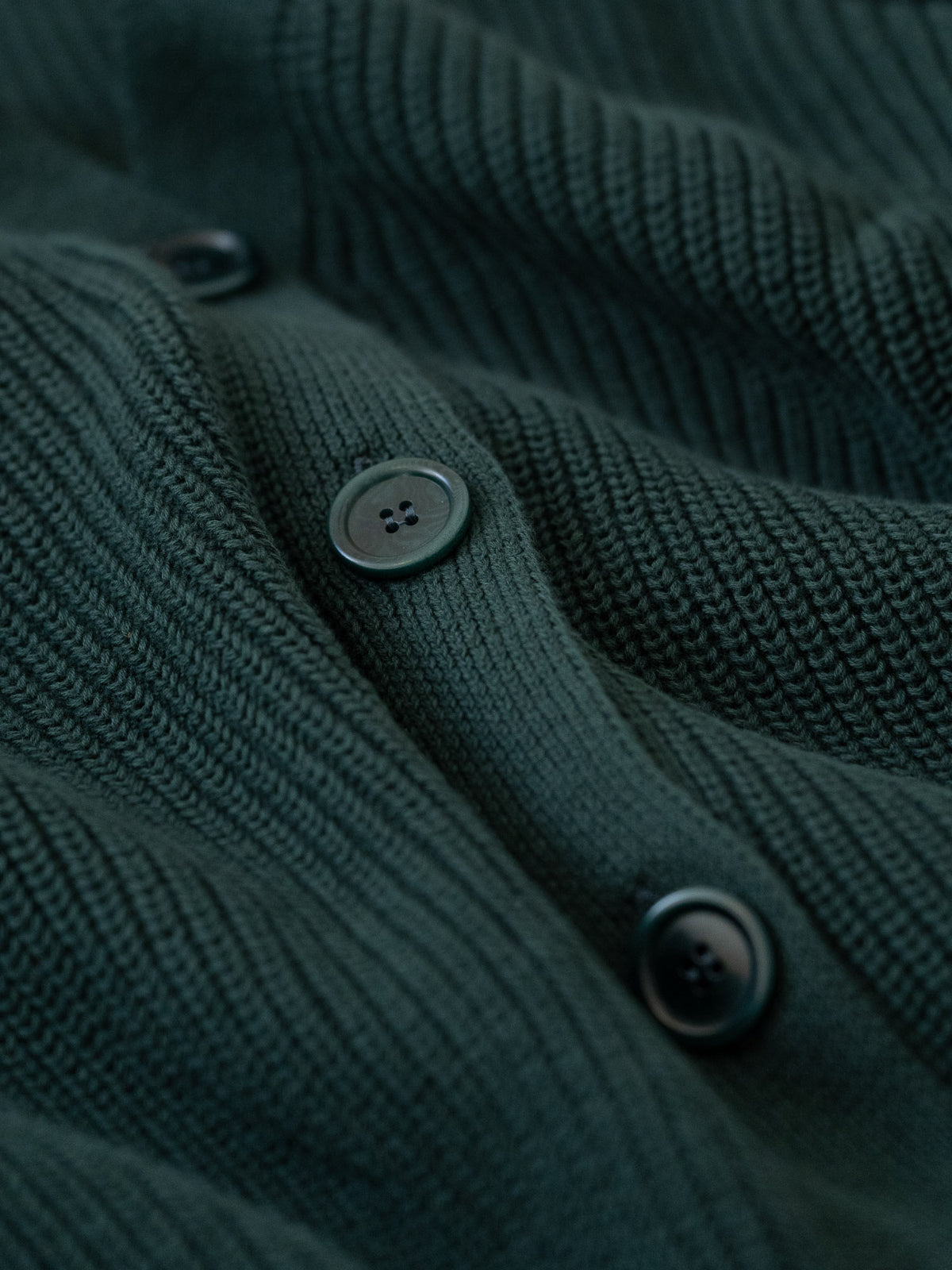 Detailansicht einer Knopfleiste von einer FUXBAU Fair Fashion Strickjacke gefertigt in Italien in dunkelgrün.