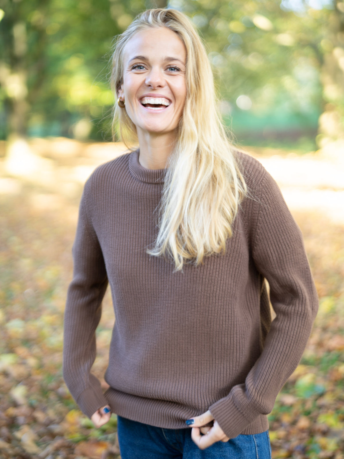 Junge blonde Frau trägt den 4Seasons Strickpullover für Frauen in braun ais 100% Biobaumwolle, GOTS zertifiziert und Made in Italien.
