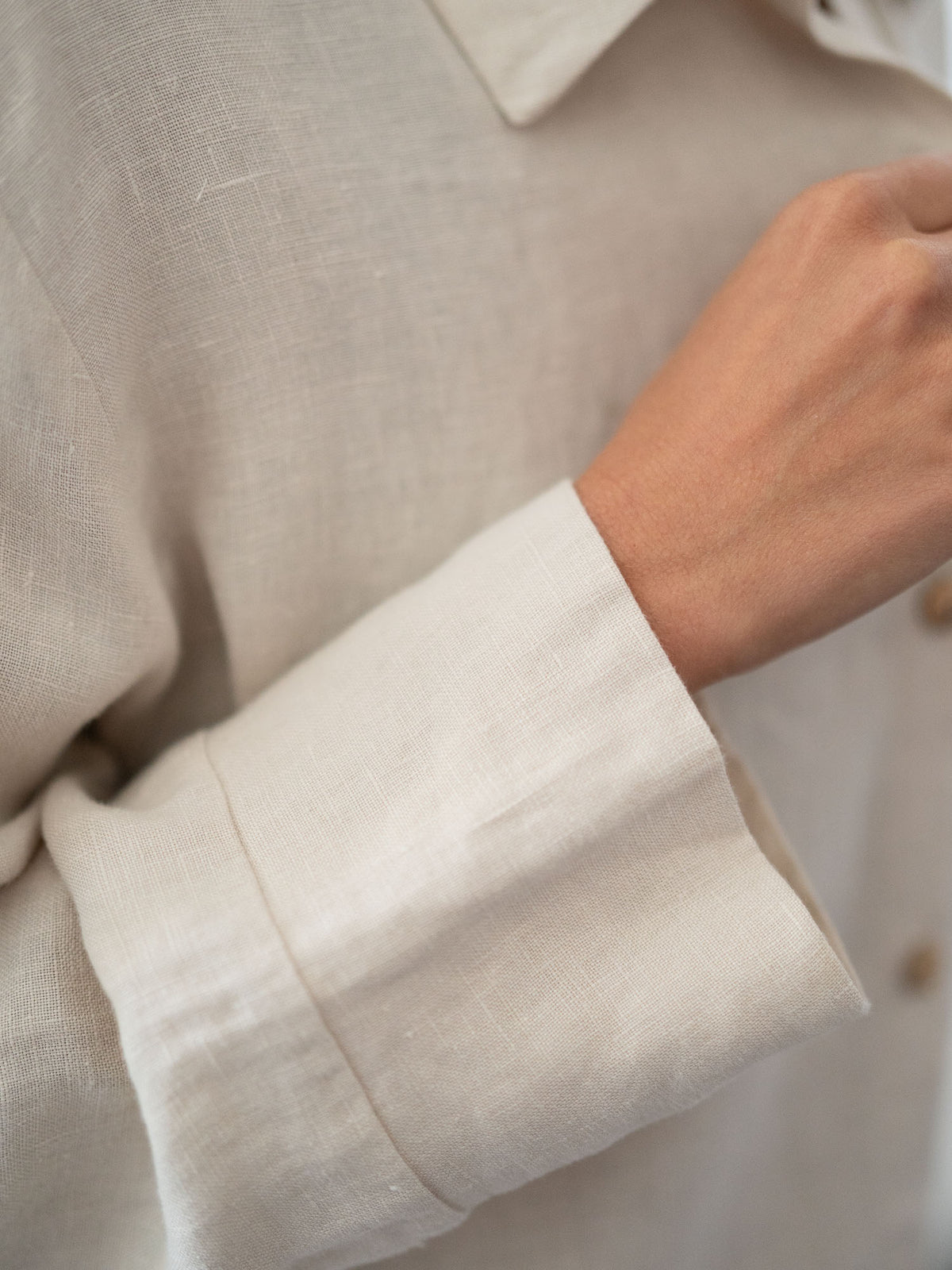 Detailansicht von einem Ärmel einer Fair Fashion Frauen Leinenbluse von FUXBAU in cremeweiss aus 100% Leinen gefertigt in Portugal unter fairen Bedingungen. Getragen von einer jungen, blonden Frau in Münster.