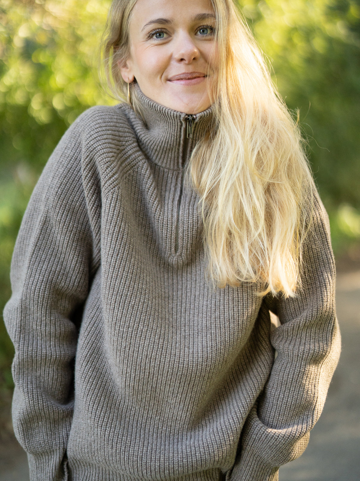 Fair Fashion Frauen Merino Troyer in braun meliert aus 100% Merino Schurwolle Made in Italy, getragen von einer jungen Frau, die in die Kamera frontal lächelt.