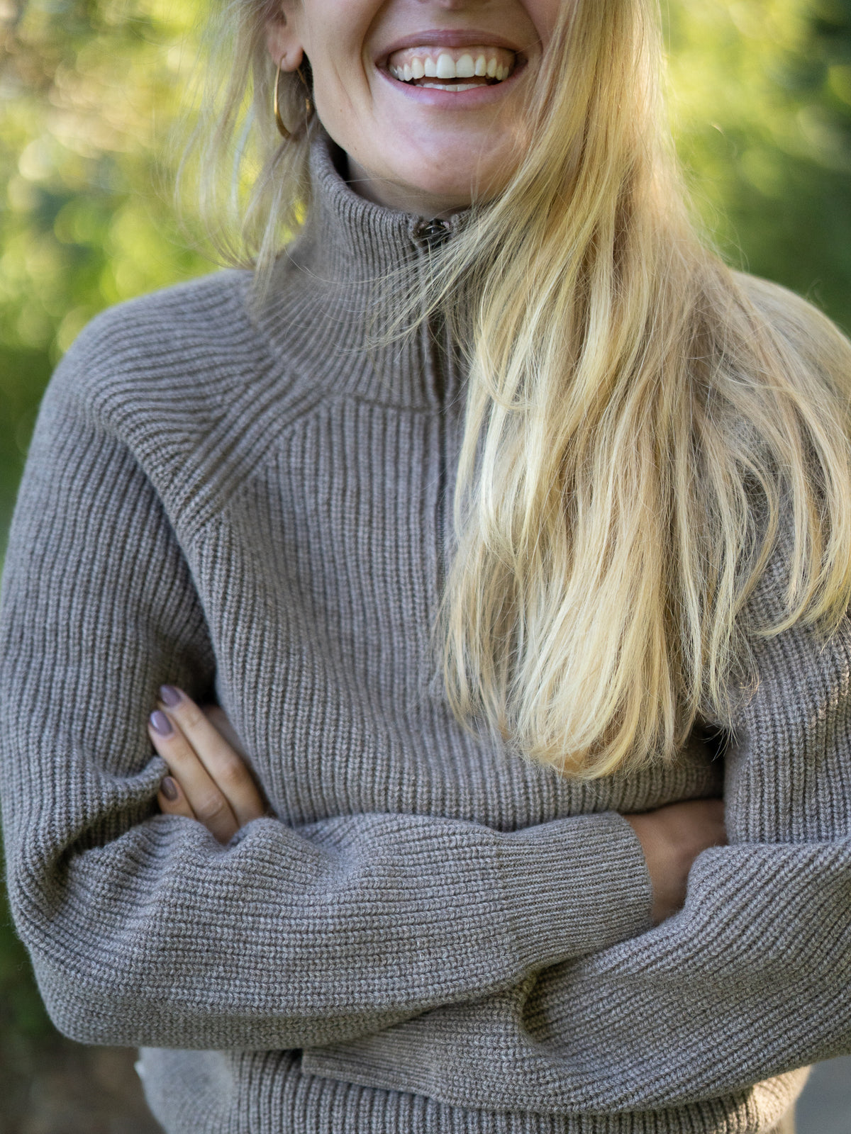 Fair Fashion Frauen Merino Troyer in braun meliert aus 100% Merino Schurwolle Made in Italy, getragen von einer jungen Frau, die in die Kamera lacht.