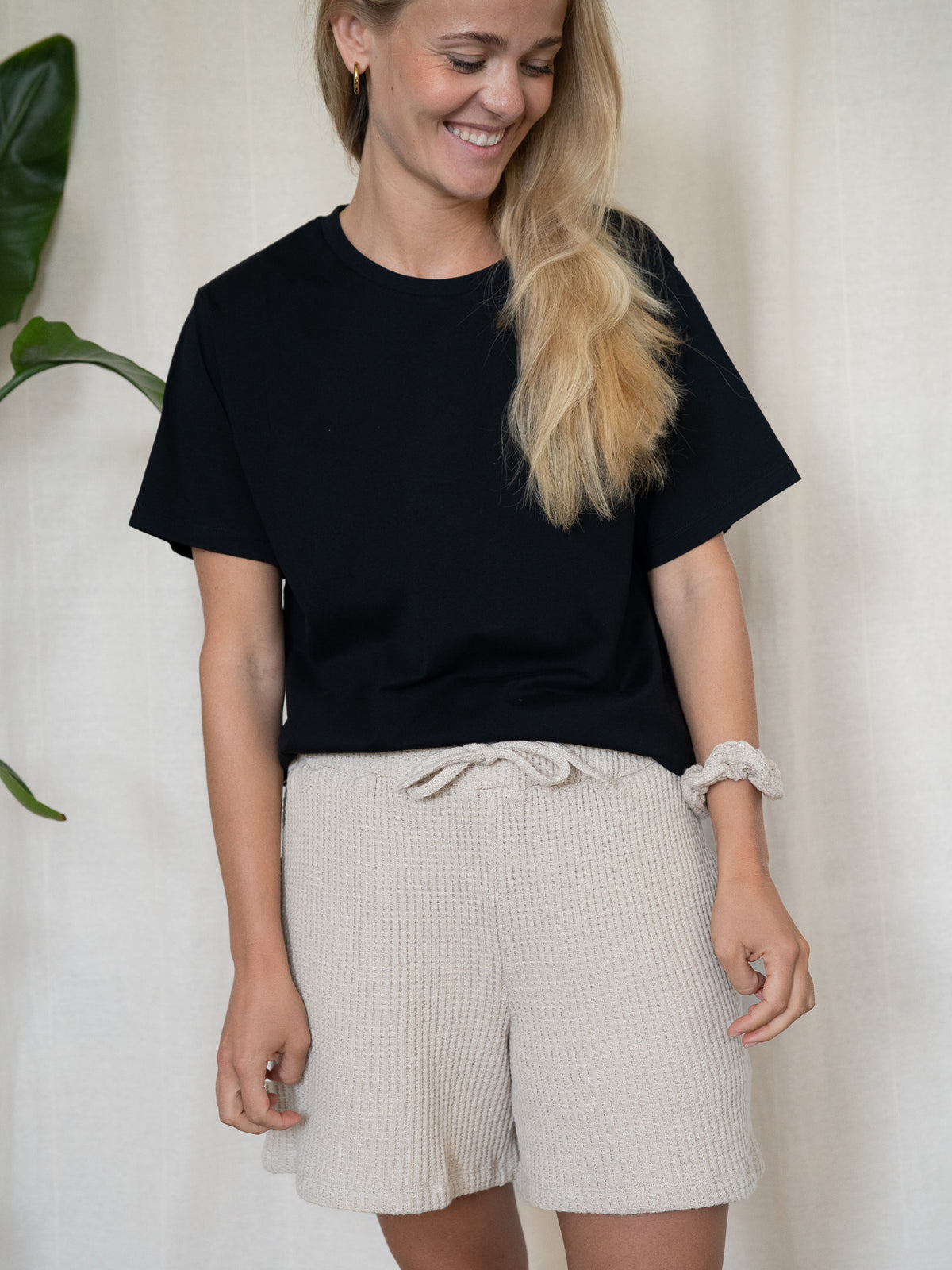 Lächelnde Frau trägt Waffelstrick Shorts für Damen in Beige – Fair Fashion Look mit schwarzem T-Shirt