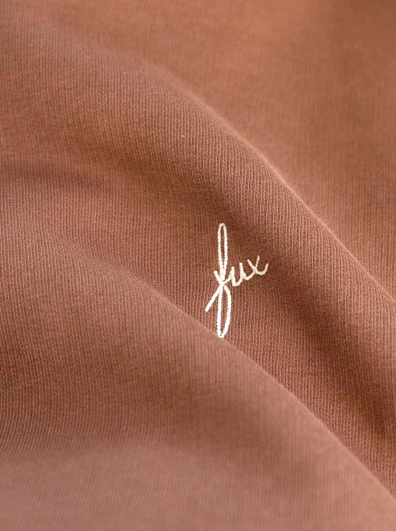 Detailansicht einer weißen fux Stickerei auf einem FUXBAU Hoodie in karamell