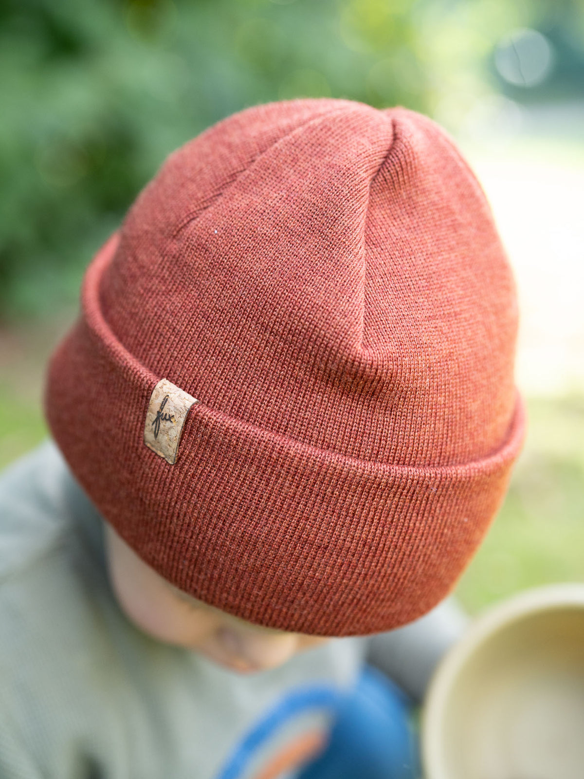 Detailansicht Kind mit herbstorangener FUXBAU Kinder Merino Kork Beanie – Kindermütze aus Merinowolle, fair gefertigt in Deutschland.